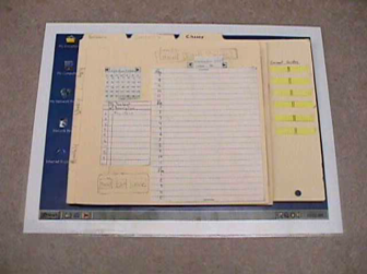 Photograph of a paper prototype for a student organizer in calendar mode. Prototype is made form white paper, manila folders & yellow sticky paper. Small photograph gives overview, but not details.