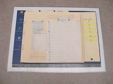 Photograph of a paper prototype scheduling program made from manila folders, paper & yellow sticky pads.